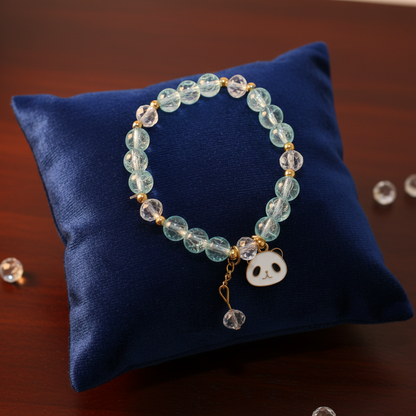 Aqua blue beaded bracelet with panda charm on velvet cushion