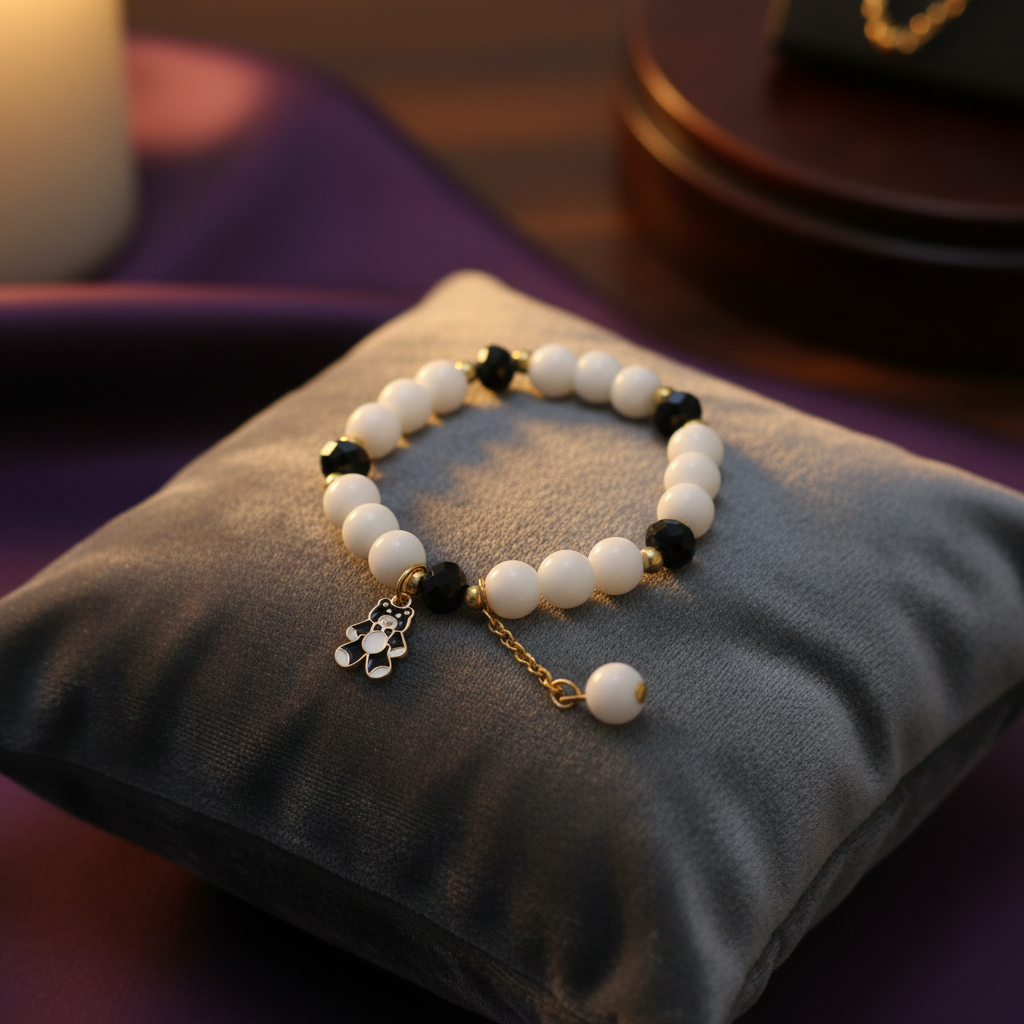 White and black beaded bracelet with panda charm on velvet cushion