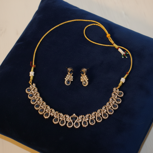Blue sapphire and gold-tone jewellery set on velvet cushion